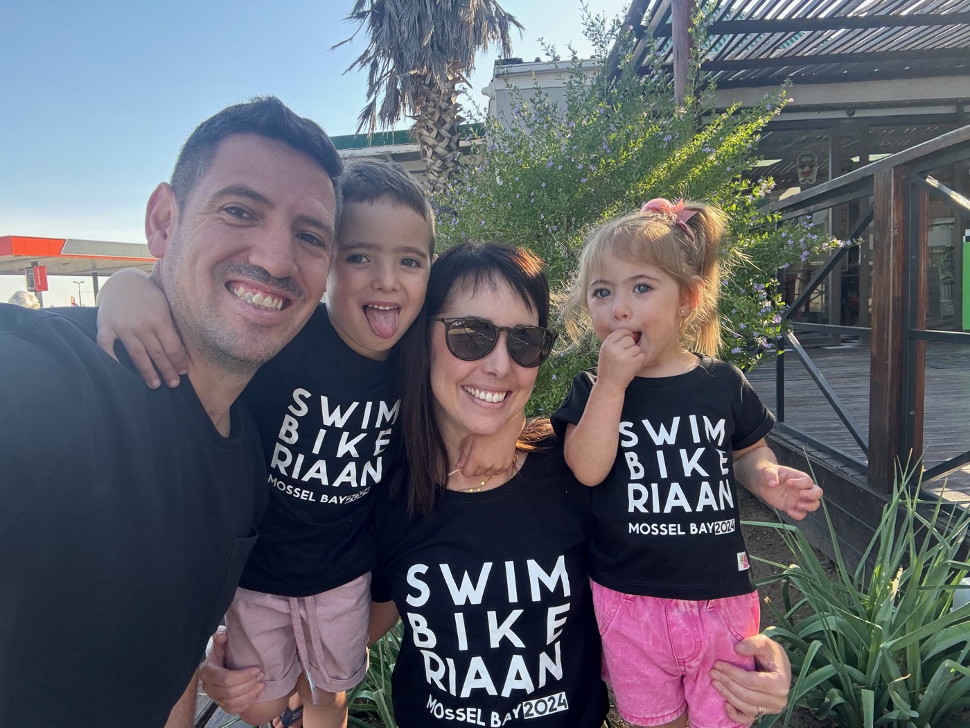 Riaan van Straaten with his wife and two kids, all in matching 'Swim Bike Riaan — Mossel Bay 2024' supporter shirts